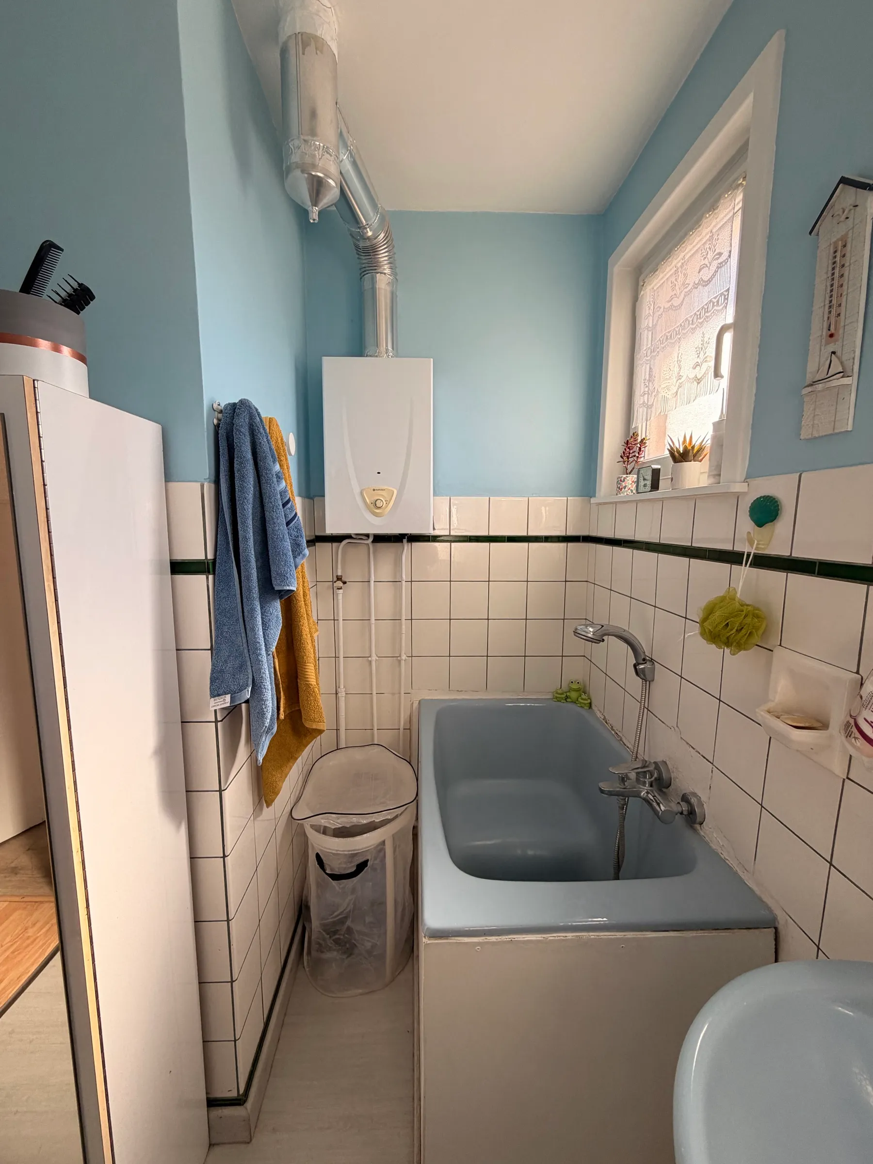 La salle de bain avant travaux - murs bleus, baignoire sabot et chauffe-eau apparent