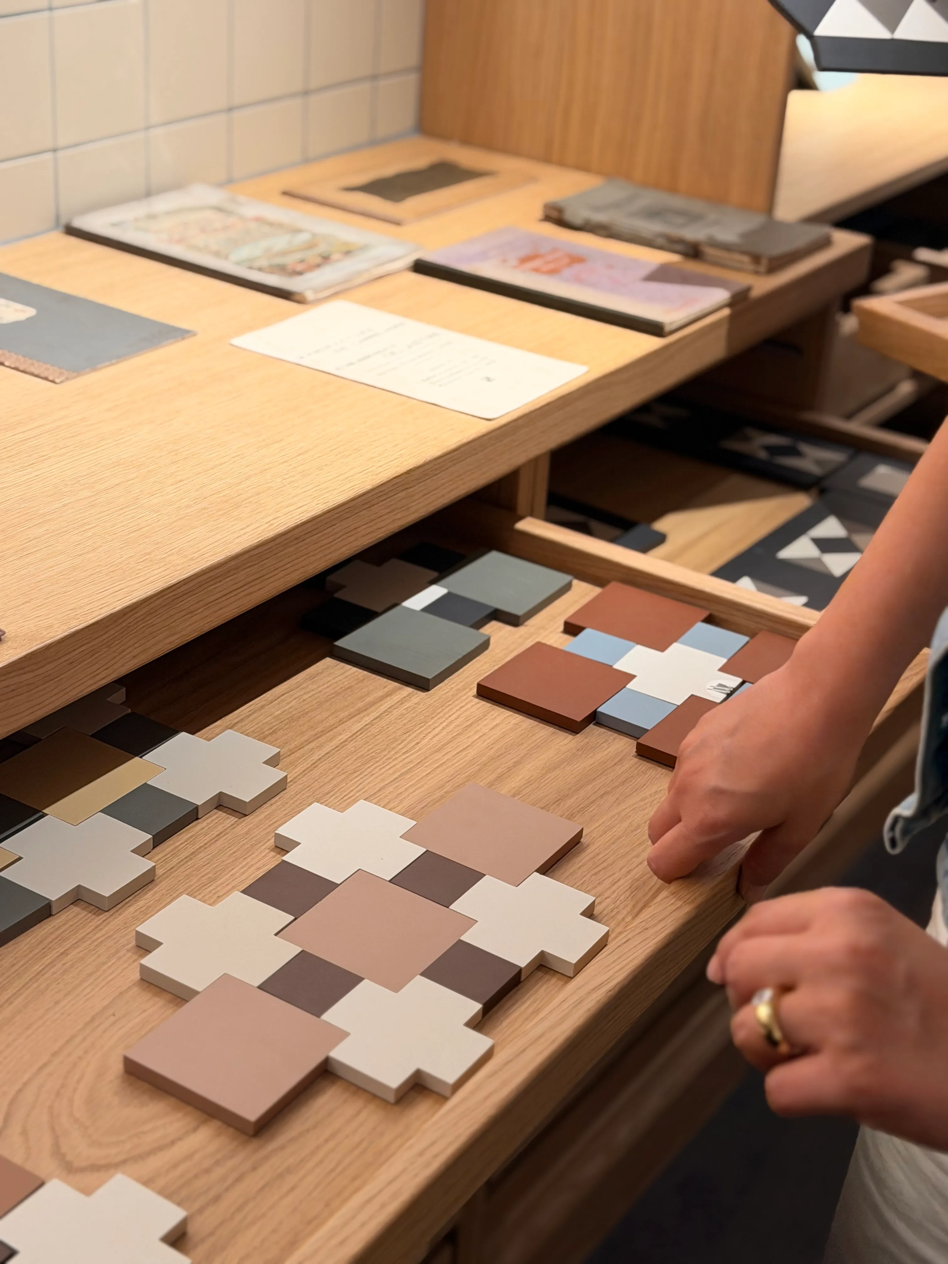 Sélection d'échantillons de carrelage aux teintes terracotta, crème et brun, sur un plan de travail en chêne