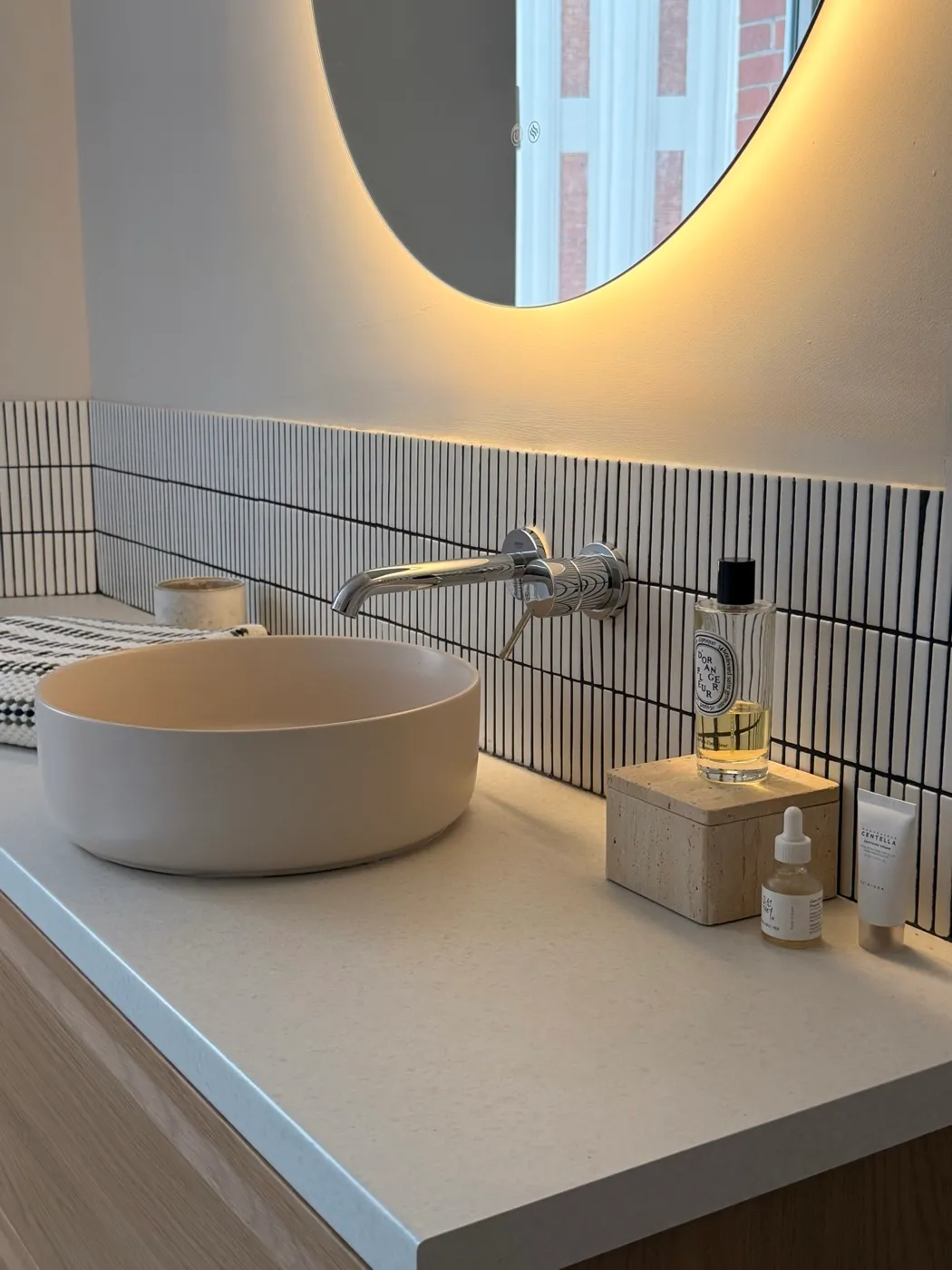 Salle de bain rénovée - vasque ronde, miroir rétroéclairé et faïence à listels