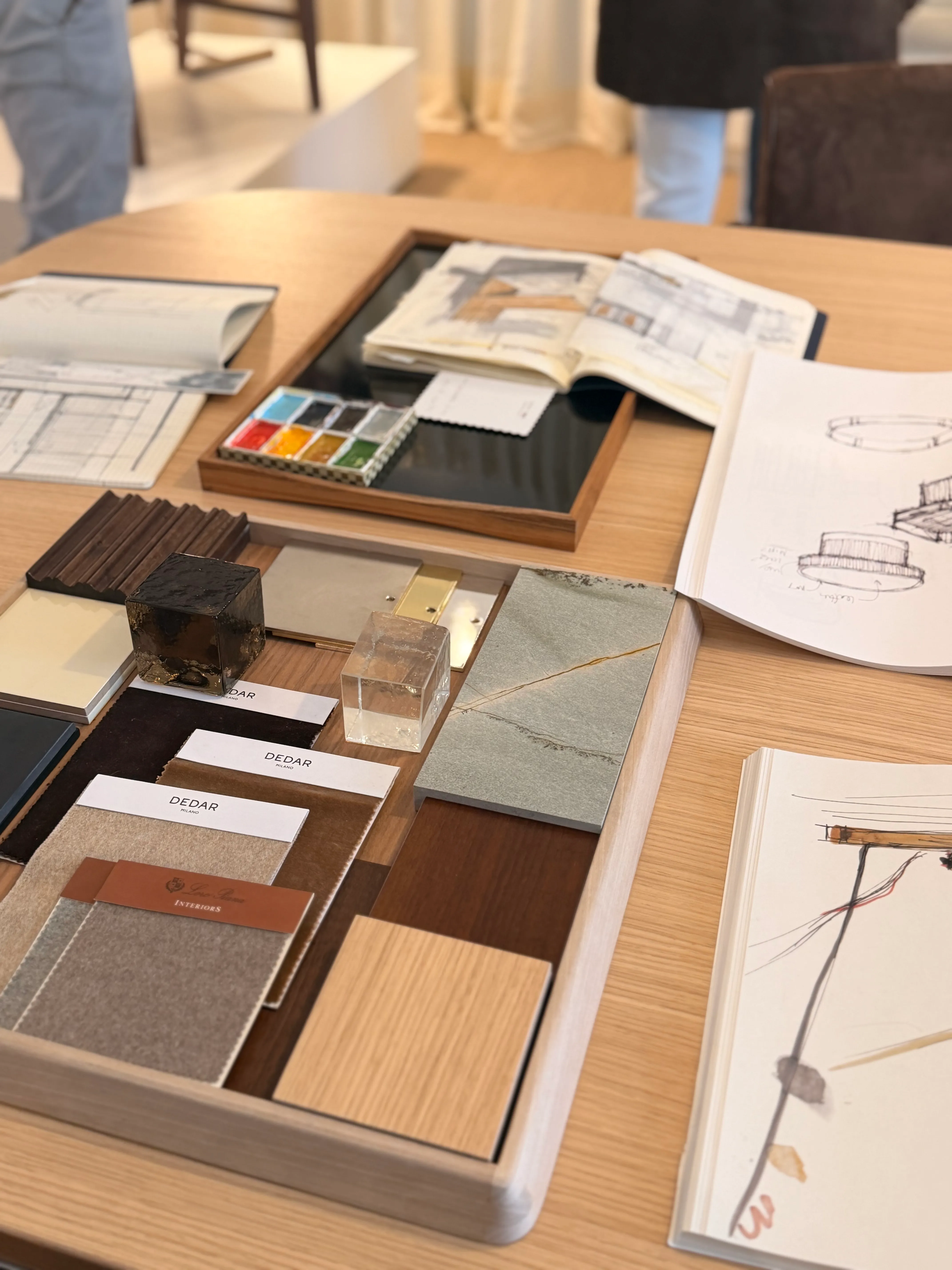 Plateau de matières sur une table en chêne : tissus, pierre, laiton, bois et croquis de mobilier